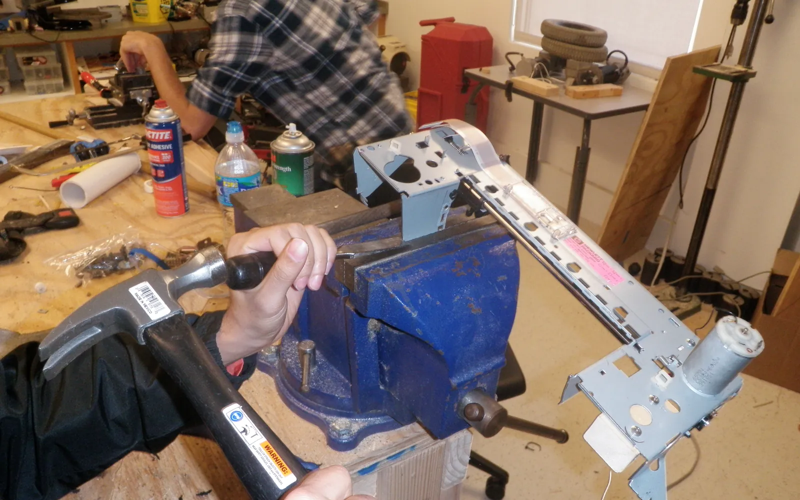 Printer chassis held in a vice on a workbench during repair